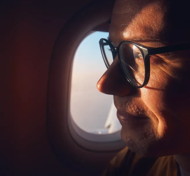 Exceptional Connectivity Photo of a man with glasses sitting on a plane staring outside the window